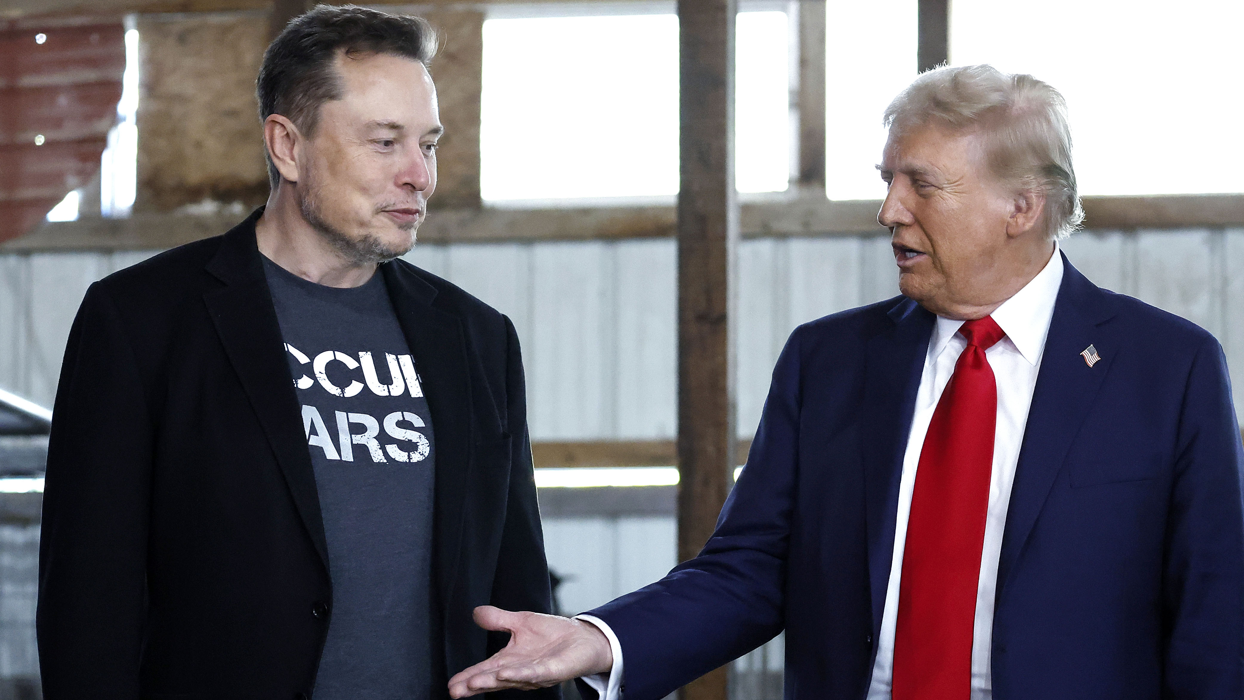 donald trump reaching his hand out to elon must for a handshake but elon ignores him